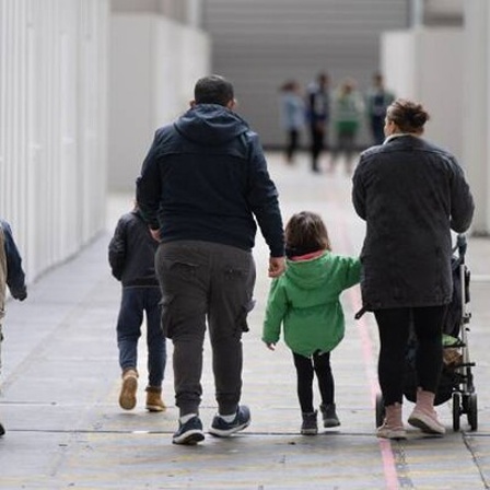 Eine Familie mit kleinen Kindern geht durch zu einer Massenunterkunft umfunktionierten Messehalle in Frankfurt.