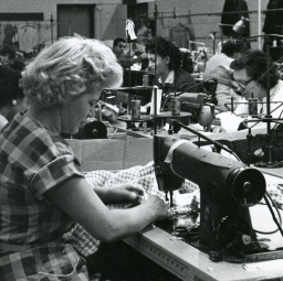 Näherin mit Nähmaschine in historischer Nähfabrik