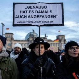 Eine Demonstrantin hält vor dem Bundestag ein Schild mit der Aufschrift "Genauso hat es damals auch angefangen" hoch.