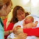 Eine Hebamme betreut Mutter und Kind nach der Geburt im Kreissaal