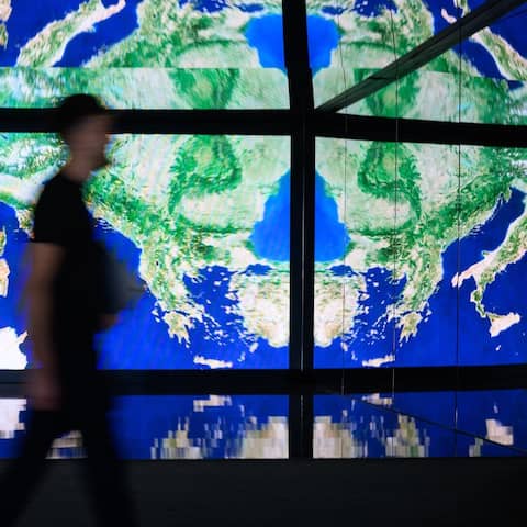 Ein Mann geht zwei Tage vor dem Start der Internationalen Luft- und Raumfahrtausstellung auf dem Gelände vom Flughafen Berlin Brandenburg (BER) im Space Pavillon an einer Wand mit großen Bildschirmen vorbei. (Bild: dpa-news/Bernd von Jutrczenka)