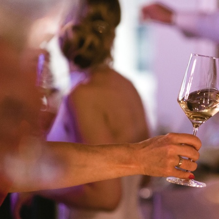 Es wird auf einer Party mit Weißwein angestoßen.