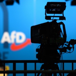Eine Fernsehkamera steht auf der AfD-Europawahlversammlung auf einem Podium. Im Hintergrund sieht man das Logo der Partei.