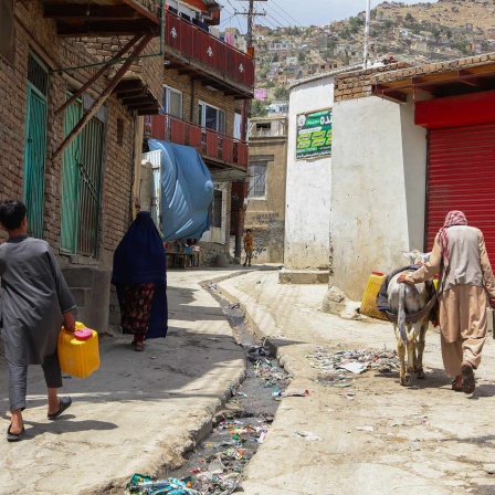 Menschen tragen Wasserbehälter in den Straßen von Kabul (Hauptstadt in Afghansitan (Bild: picture alliance))