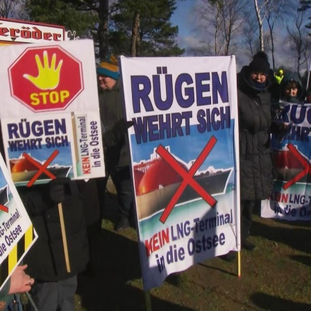 Menschen protestieren mit Schildern gegen ein LNG-Terminal auf Rügen