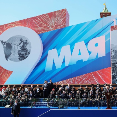 Wladimir Putin hält am &#034;Tag der Befreiung&#034;, dem 9. Mai 2023, eine Rede in Moskau. Hinter ihm eine riesige Plakatwand, auf der u. a. zu lesen ist &#034;1945 - 2023&#034;. Ganz links auf der Wand ist das ikonische Foto zu sehen, auf dem sowjetische Soldaten im Mai 1945 die rote Flagge auf dem Berliner Reichstag installieren und damit den Sieg über Nazi-Deutschland feiern. Im russischen Angriffskrieg gegen die Ukraine setzen beide Parteien immer wieder auf Propaganda - auch die Ukraine.