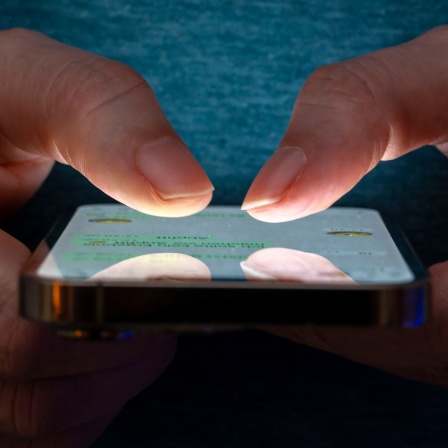 Eine Frau tippt auf einem Smartphone-Screen.