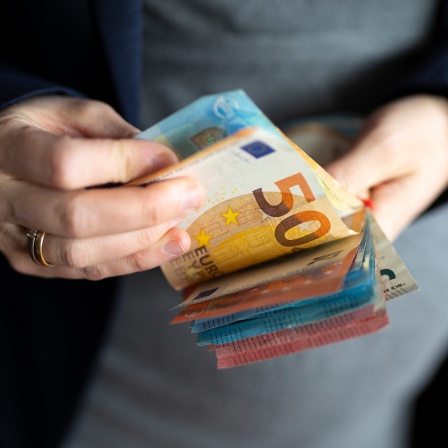 Eine Frau hält mehrere Euro-Scheine in der Hand.