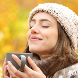 Zufriedene Frau mit Kaffee im Herbst