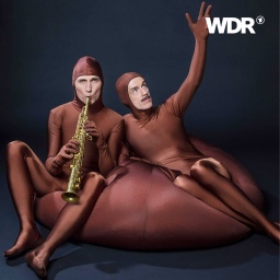 Lieven Brunkhorst mit Klarinette und Jacques Palminger mit theatralisch zum Himmel gereckter Hand, auf einem Sitzsack posierend.