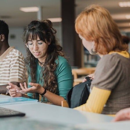 Studierende sitzen in einem Arbeitsraum und sprechen miteinander