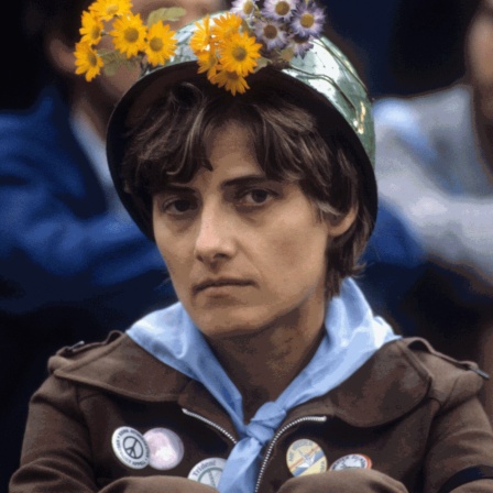Petra Kelly mit Stahlhelm, der mit Blumen dekoriert ist