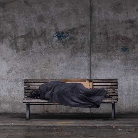 Das Beitragsbild des Dok5 "Angst haben fast alle - Gewalt im Leben von Obdachlosen" zeigt einen schlafenden Obdachlosen auf einer Bank in Berlin.