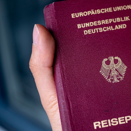 Ein Deutscher Reisepass in der Hand einer Frau. 