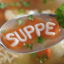 Ein Suppenlöffel mit Suppe, deren Buchstabenförmige Nudeln das Wort "Suppe" zeigen.
