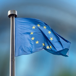 Die Flagge der Europäischen Union vor verschwommenem Hintergrund.