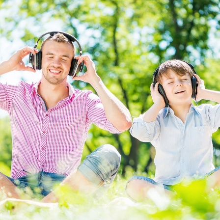 Ein Mann und ein Junge hören über Kopfhörer Musik.