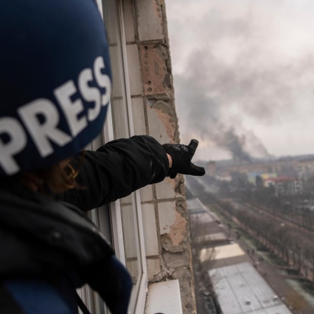 Pressefotografin Evgeniy Maloletka zeigt auf die qualmende Stadt Mariupol nach einem Luftangriff
