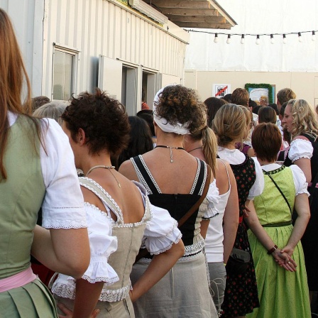 Frauen in einer Warteschlange an einer öffentlichen Toilette.