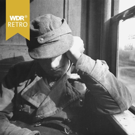 Ein Heimkehrer sitzt 1946 im Bahnabteil.
