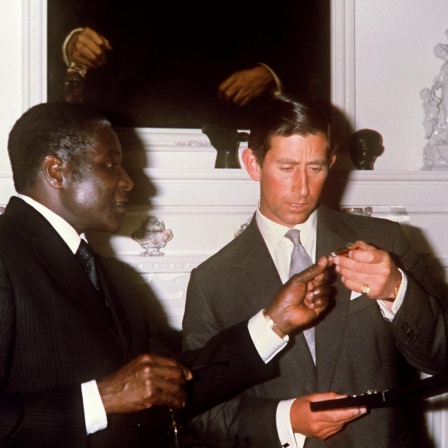 Robert Mugabe  überreicht im Rahmen eines feierlichen Abendessens im Regierungssitz in Salisbury Mitte April 1980 dem britischen Thronfolger Prinz Charles eine Unabhängigkeitsmedaille. Die ehemalige britische Kolonie Rhodesien wurde nach den Wahlen im Februar 1980 am 18.4.1980 unter dem Namen Simbabwe unabhängig. Erster Premierminister des neuen Landes wurde im März 1980 Robert Mugabe. Prinz Charles nahm an den Feierlichkeiten zur Unabhängigkeit teil.