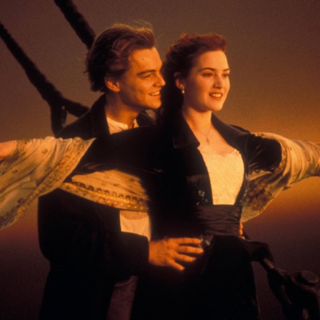 Ein Filmstill aus &#034;Titanic&#034; (1997): Jack (Leonardo DiCaprio) und Rose (Kate Winslet) stehen im Sonnenuntergang am Bug der Titanic
