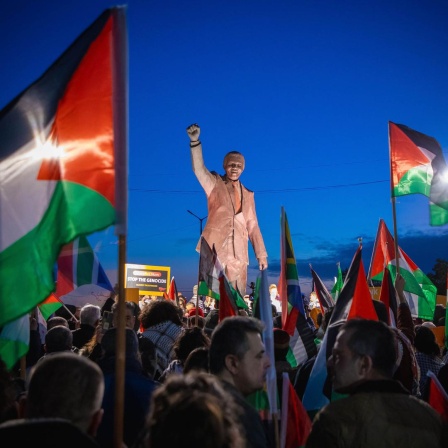 Palästinenser mit Fahnen und Spruchbändern auf dem Nelson-Mandela-Platz mit Mandela-Statue mit geregter Faust in Ramallah im Westjordanland. Anlass war die von der Republik Südafrika beim Internationalen Gerichtshof (IGH) eingereichte Klage wegen mutmaßlichen Völkermords gegen Israel.