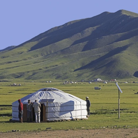 Mongolische Männer vor einem traditionellen Ger, einer mit Solarzellen ausgestatteten Jurte in der Steppe der Mongolei im Sommer.