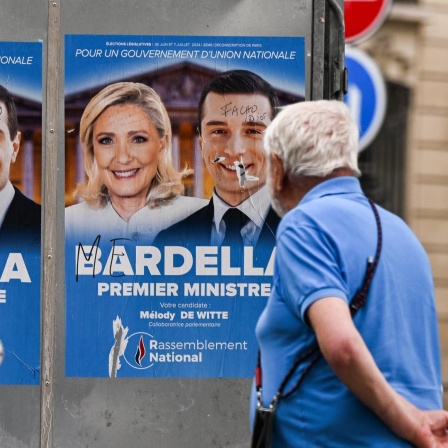 Ein Mann steht vor Wahlplakaten