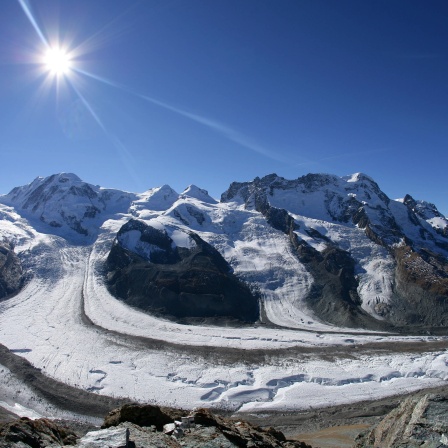 Blick vom 3089 Metern hohen Gornergrat auf den Grenz- und Gornergletscher in den Alpen unweit von Zermatt - der Gletscher schmilzt allmählich unter der starken Sonneneinstrahlung am blauen Himmel.