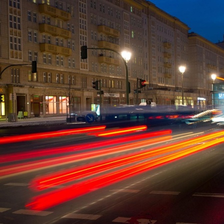 Die Rücklichter eines fahrenden Autos auf der Karl-Marx-Allee in Berlin.