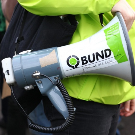 Ein Demonstrant hält ein Megafon mit einem Aufkleber mit der der Ausfschrift "BUND" - für Bund für Umwelt und Naturschutz Deutschland - bei einer Demonstration