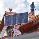 Solarmodule werden auf ein Hausdach transportiert.