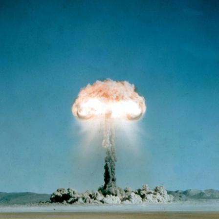 Ein Atompilz steigt in einer Wüstenlandschaft auf.