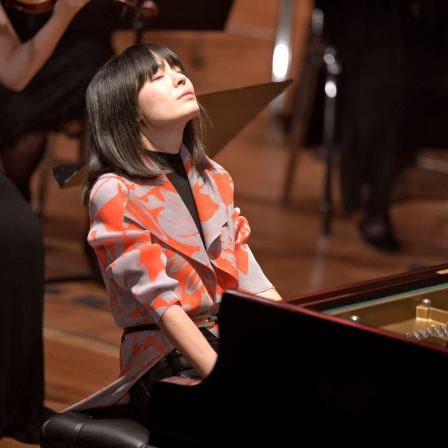 Die Pianistin Alice Sara Ott: Frau mit geschlossenen Augen und dunklen, glatten Haaren am Flügel während eines Konzerts