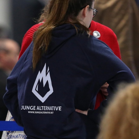 Auf einem Parteitag der AfD ist eine junge Frau in einem Kapuzenpullover der AfD-Jugendorganisation "Junge Alternative" von hinten zu sehen.