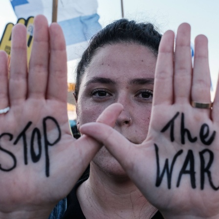 Anti-Kriegs-Demonstrationen in Israel: Eine Frau hält ihre Hände in die Kamera, auf denen &#034;Stop the War&#034; steht