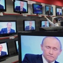 Wladimir Putin ist in einem Geschäft auf diversen TV-Bildschirmen zu sehen.