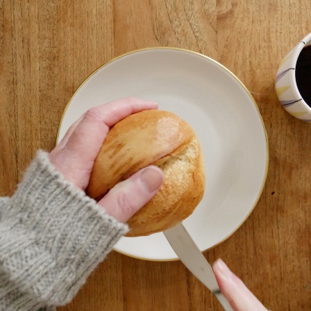 Ein Brötchen wird auf Teller aufgeschnitten.