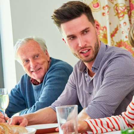 Familie mit Großvater und Enkel zusammen beim Mittagessen am Esstisch