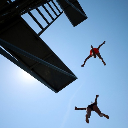 2 Jungen springen von einem Sprungbrett im Freibad