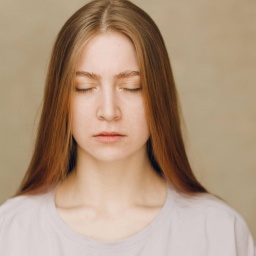 Portrait of young sad upset caucasian woman looking at camera against beige background