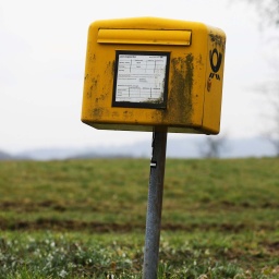 Ein schmutziger Briefkasten auf einer Wiese.