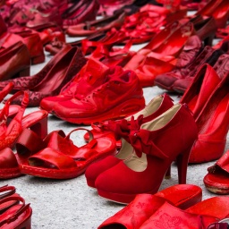 Auf einer Straße in der Nähe der Piazza Garibaldi in Gagliari auf Sardinien sind zahlreiche blutrot angemalte Schuhe aufgereiht.