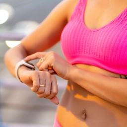 Sportliche Frau trackt ihre Körperdaten auf einer Smartwatch