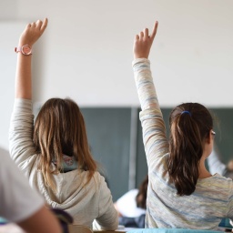 Schülerinnen melden sich in der Klasse.