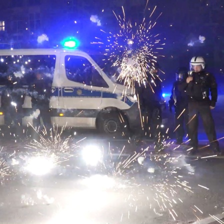 Polizeibeamte stehen hinter explodierendem Feuerwerk in der Silvesternacht © pa/ dpa/ TNN/ Julius-Christian Schreiner