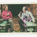 Zwei Frauen sitzen mit Mikrofonen auf Kindertrekkern.