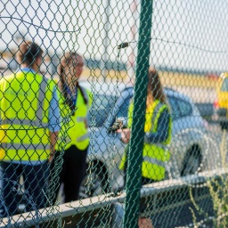 Fraport-Mitarbeiter stehen an dem zerstörten Zaunabschnitt (l), durch den die Klimaaktivisten auf das Flughafengelände in Frankfurt am Main eingedrungen sind.