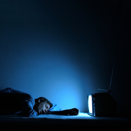 Ein Mann  schläft vor einem Fernseher